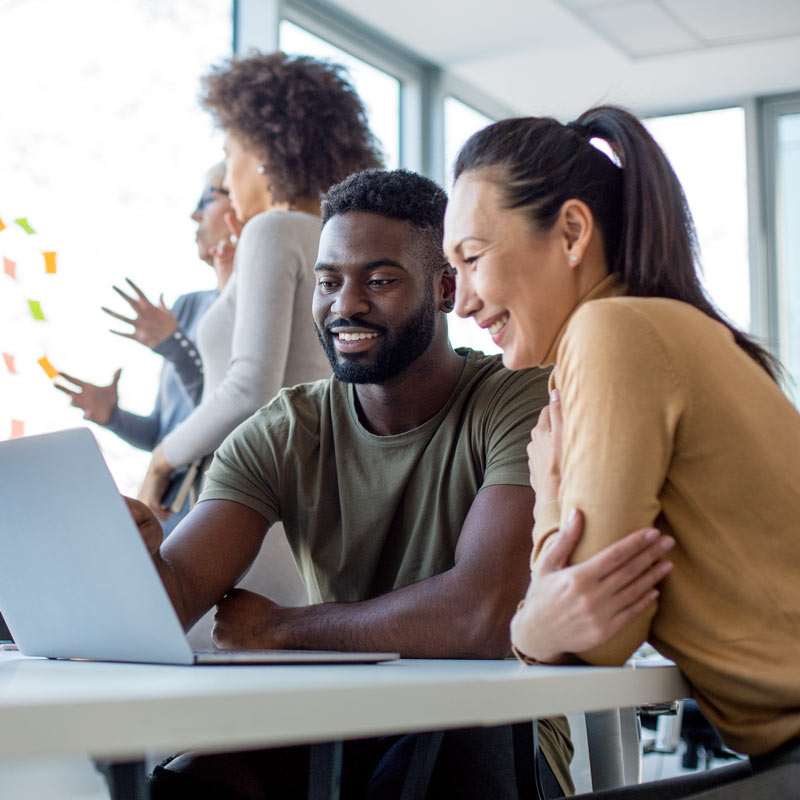 Two people in an office in front of a laptop.